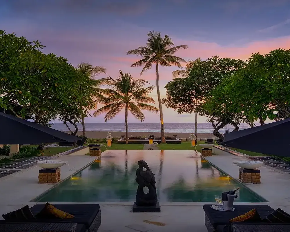 A villa pool framed by palms at sunset