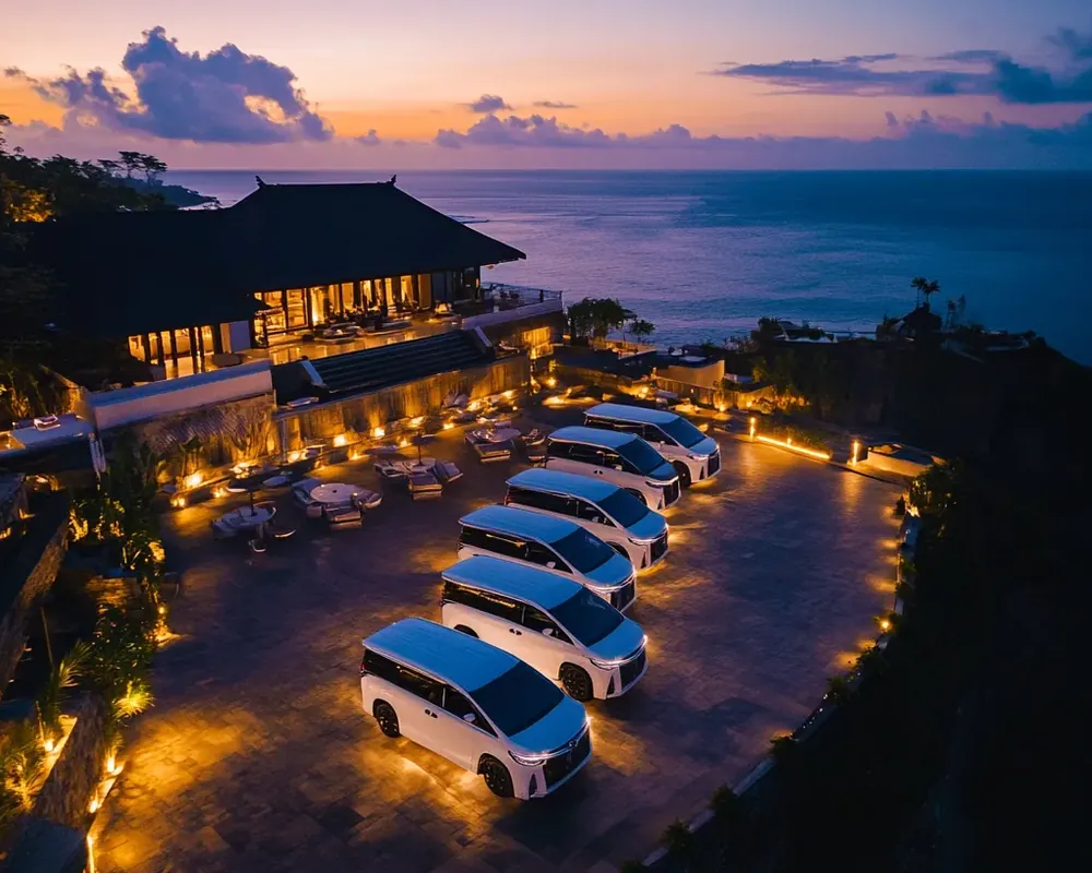A cliff-top resort at dusk with a row of vehicles lit by lanterns