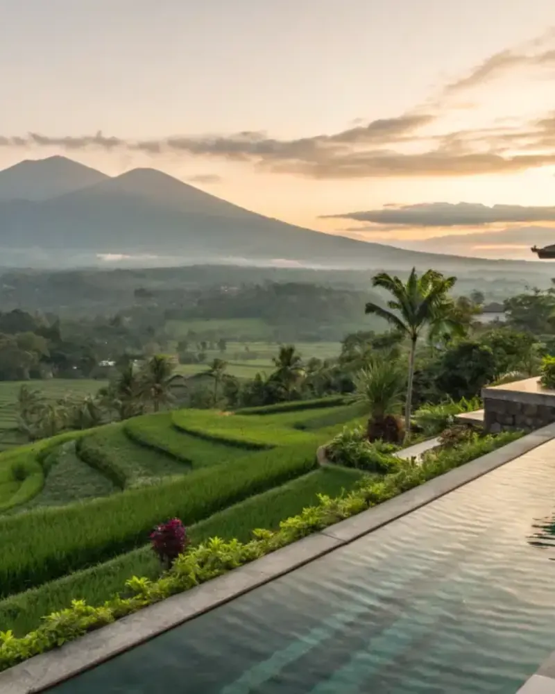 Rice terraces and volcano at sunset beyond a villa infinity pool