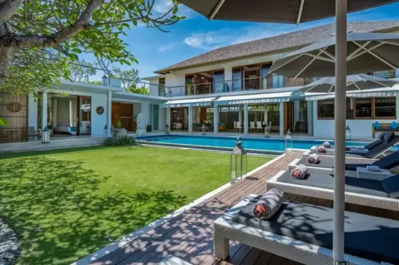 A villa pool beside a thatched-roof pavilion